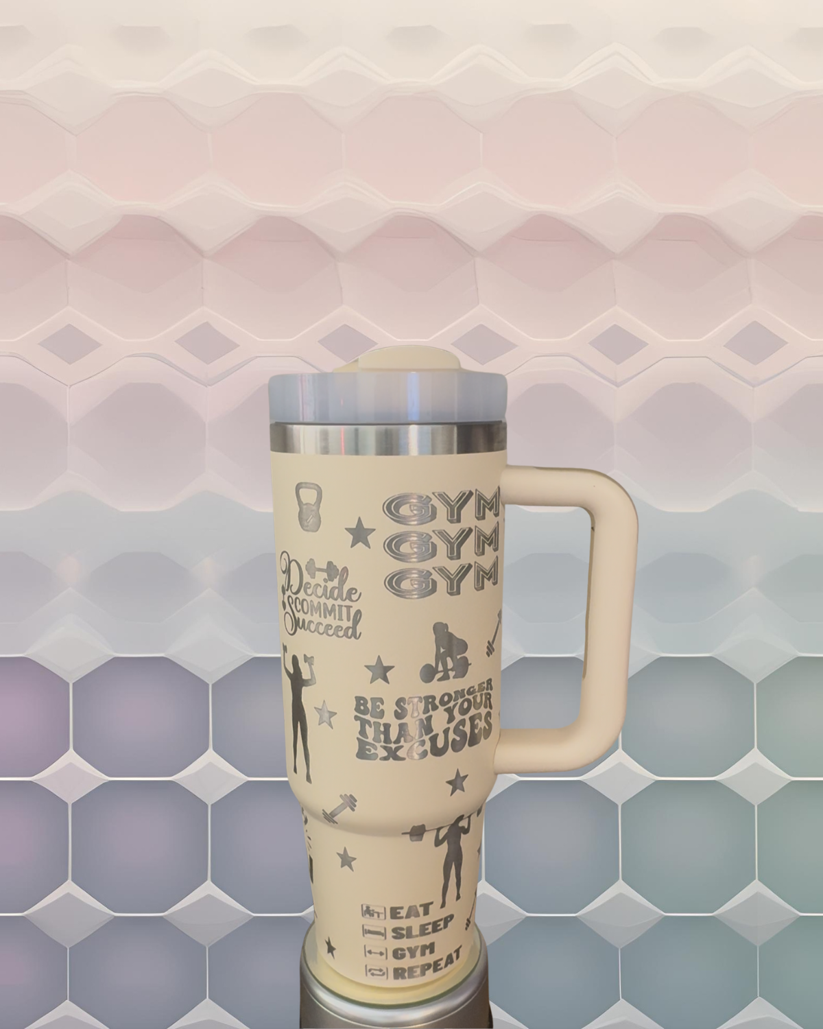 A large beige thermos mug with various fitness-related phrases and illustrations printed on it, set against a colorful geometric background.