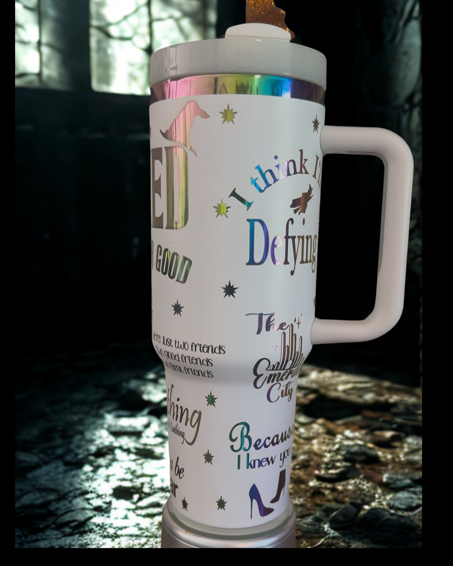 A tall, white, and colorful insulated tumbler mug with various text and graphics printed on it.