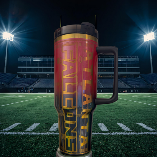 A large, colorful thermos mug with the word "ATLANTA" printed on it, placed on a football field with stadium lights in the background.