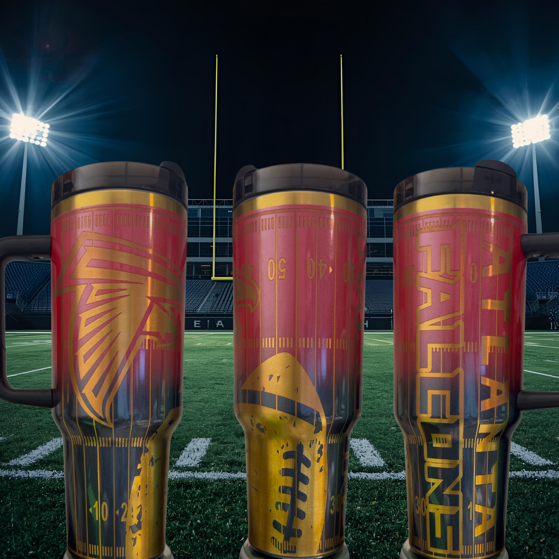 Three large, colorful tumblers with football designs on them, placed on a football field at night with stadium lights in the background.